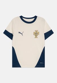 Maglietta sportiva bianca e blu navy con colletto e polsini blu navy, logo Puma sul lato sinistro del petto e un'emblema a forma di scudo giallo sul lato destro del petto.