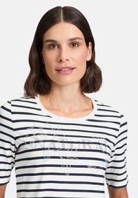 Striped short-sleeve T-shirt with a white base and navy stripes, featuring a rhinestone floral design on the front.
