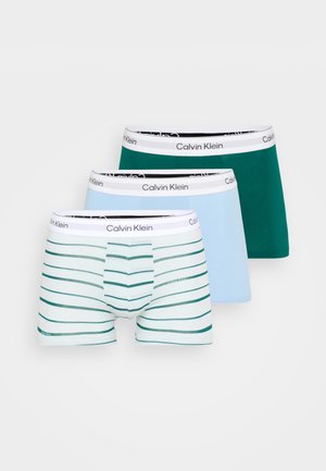 Trīs pāri Calvin Klein bokseršortus: viens zaļš, viens gaiši zils un viens gaiši zils ar zaļām horizontālām svītrām un melnu logotipa elastīgo jostasvīru.