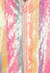 Monivärinen paljettikangas pystysuoralla raitakuviolla, jossa on vaaleanpunaista, oranssia, keltaista ja purppuraa, sekä keskeinen vetoketjuyksityiskohta.