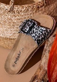 Leopardprint slipper sandaal met een brede band en een zwarte gespsluiting, een suède-achtige binnenzool en een witte rubberen zool.