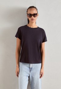 Zwarte T-shirt met korte mouwen van zachte stof, met een ronde halslijn en een losse pasvorm, gecombineerd met lichtblauwe hoge taille jeans.