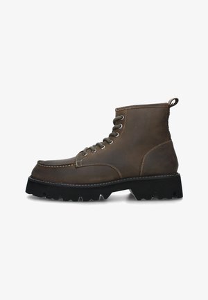 Stivale alla caviglia in pelle marrone, con punta rotonda, chiusura con lacci, cuciture bianche a contrasto, linguetta e suola in gomma nera robusta.
