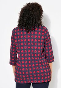 Camicia a maniche lunghe rossa e blu navy con un motivo geometrico. Presenta un collo rotondo e una vestibilità rilassata, realizzata in tessuto morbido.
