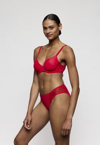 Rode set ondergoed met een beha met gevormde cups en bijpassende hoge taille slips, gemaakt van zachte stof met een minimalistisch ontwerp.