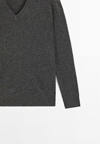 Maglione grigio a scollo a V realizzato in morbido materiale a maglia, con maniche lunghe e orlo a coste. Design semplice con una texture liscia.