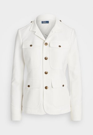 Valkoinen räätälöity takki, jossa neljä etutaskua läpällä, kullanväriset napit ja lovikaulus, sisältä Polo by Ralph Lauren -etiketti.