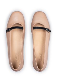 Ballerines en cuir beige clair avec un bout rond, présentant une sangle noire avec un accent circulaire argenté et une doublure intérieure lisse et douce.