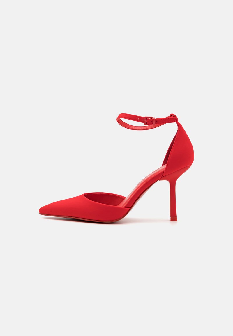 Červená lodička s vysokým podpätkom a špicatou špičkou, so zavesením na členku, hladkým povrchom a štíhlym stiletto podpätkom. Minimalistický dizajn, bez ozdôb.