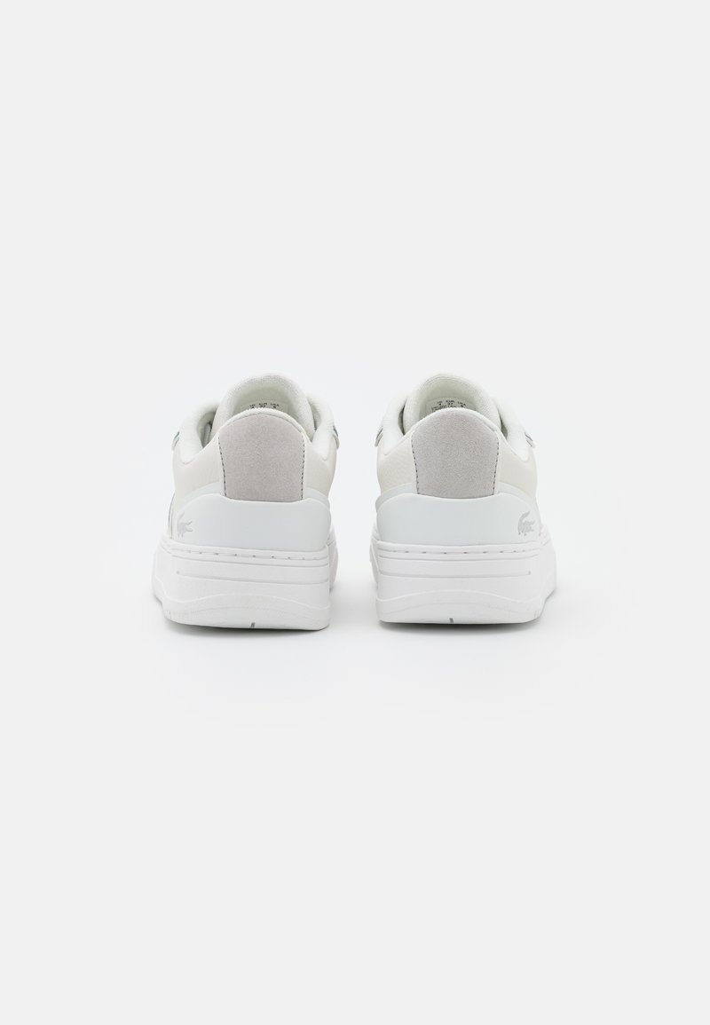 Baskets en cuir blanc avec une finition lisse, accents discrets en daim gris sur le talon, semelle texturée et design minimaliste.