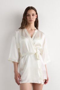 Vit satin kimono-robe med omslagdesign, V-hals, vida ärmar och tygbälte. Slät textur med subtil lyster, knälång modell.