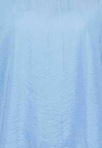 Top azzurro chiaro con una texture stropicciata e una vestibilità comoda, realizzato in un tessuto morbido e leggero. Senza decorazioni visibili.