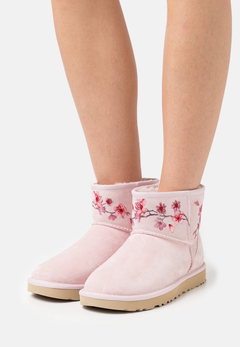 Botas de tobillo de ante rosa con bordados florales en tonos rojos y rosas, con un interior suave y suela de goma.