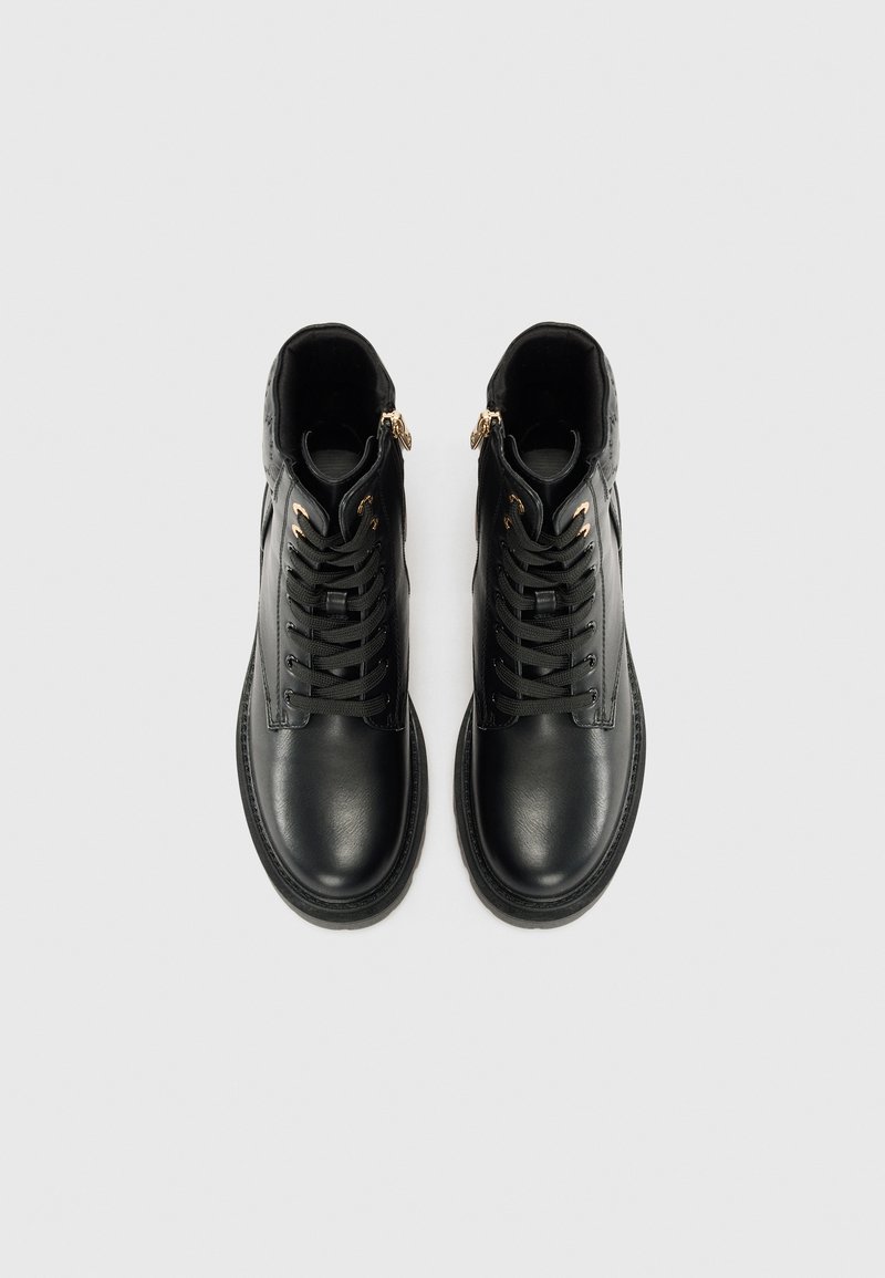 Stivali in pelle nera con una texture liscia, dotati di lacci tradizionali, due cerniere dorate e una punta rotonda. Design con suola piatta.