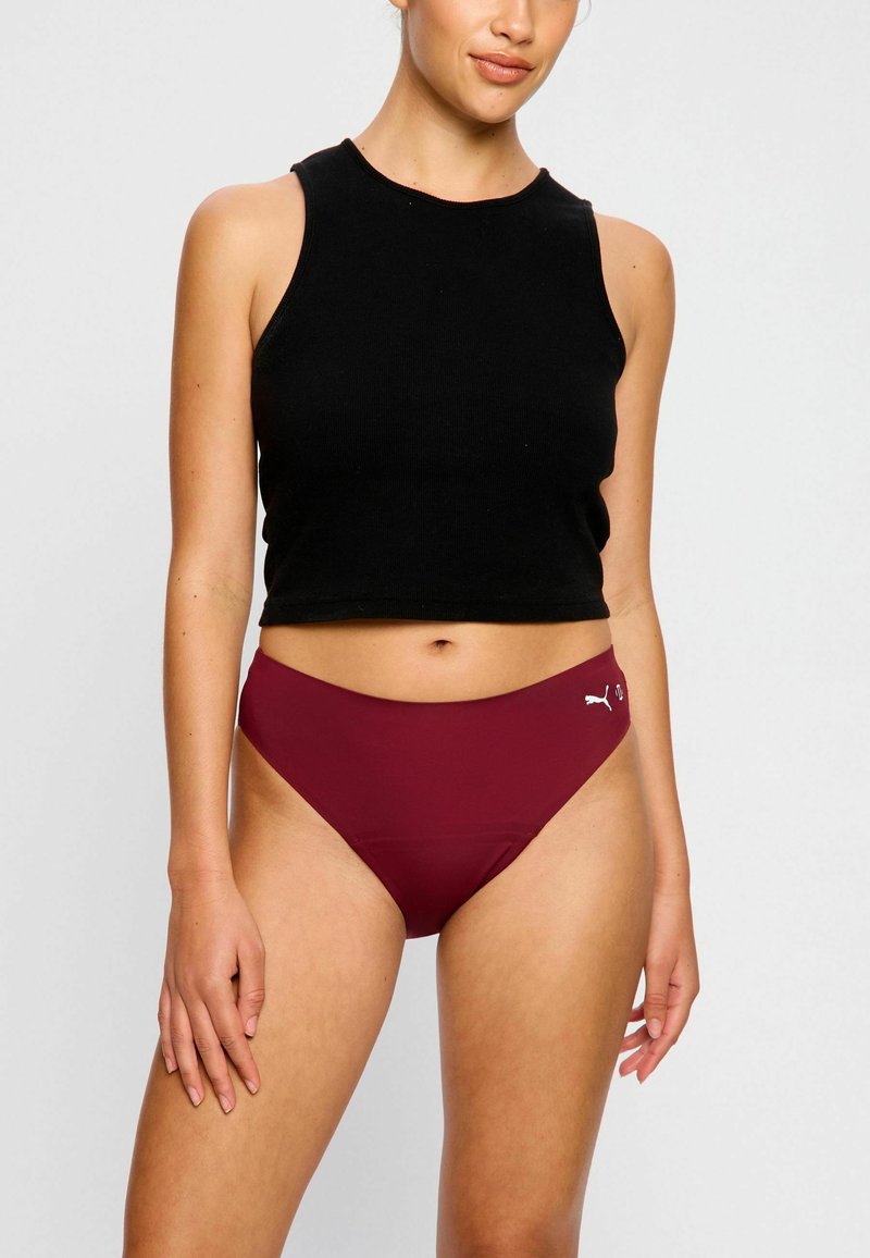 Top noir sans manches avec une texture côtelée, associé à un bas de bikini taille haute bordeaux avec un logo sur le côté.