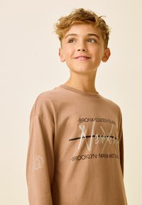 Brun långärmad sweatshirt med grafisk tryck som har "New York" och namn på städer. Tillverkad av bomull, avslappnad passform och ribbade detaljer vid halsen.