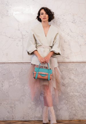 Light gray kimono-style jacket with wide sleeves, paired with a layered pink tulle skirt. Features a turquoise and peach handbag.