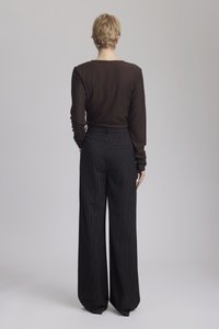 Long-sleeve brown top paired with high-waisted, wide-leg black pinstriped trousers. The trousers feature a back pocket detail.