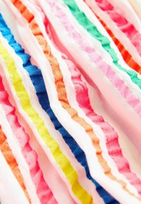 Tissu en coton coloré présentant des rayures froncées en rose, orange, vert, jaune et bleu, créant un effet texturé et superposé.