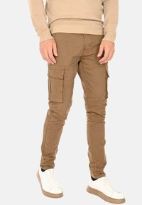 Pantaloni cargo in cotone color sabbia con vestibilità slim, dotati di due tasche laterali con pattina, dettagli cuciti e una texture liscia.