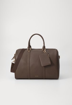 Brun lær duffel bag med gullfiner, doble håndtak og en avtakbar skulderstropp. Inkluderer en matchende bagasjelapp. Teksturert finish.