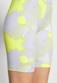 Lila och gula mönstrade träningsshorts i stretchigt material med en figurnära design; har en liten vit Nike-logotyp på nederkanten.