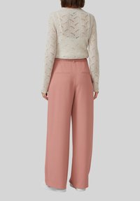 Lichtroze wijde broek met een gladde textuur, voorzien van riemlussen en achterzakken, gecombineerd met een witte gebreide top met structuur.