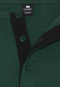 Grøn bomulds skjorte med knap-ned krave, to grønne knapper og en kontrasterende sort placket. Taget læser "DOVRE MEDIUM."