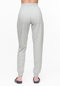 Graue Jogginghosen aus Baumwolle mit zulaufenden Beinen, elastischem Bund und gerippten Bündchen. Kombiniert mit schwarzen Slides.