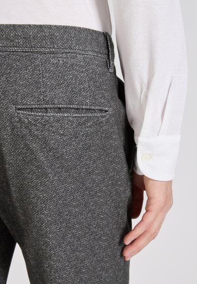 Szare spodnie w kratę houndstooth z teksturowanym wykończeniem, z tylną kieszenią i wysokim stanem, połączone z białą koszulą z długim rękawem z guzikami.