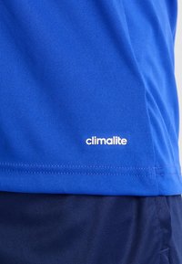 Sininen kosteutta siirtävä paita, joka on valmistettu kevyestä kankaasta. Vivid näkyvä "climalite" -logo valkoisena helman lähellä. Sileä pinta.