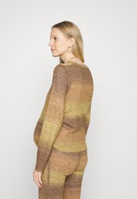 Sweater tricotado em tons degradê de castanho e amarelo, com decote redondo, mangas longas e um corte descontraído. Leggings texturizadas a condizer.