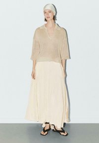 Beige gebreid topje met korte mouwen en open kraag, gecombineerd met een luchtige, lichtgele rok en zwarte sandalen. Eenvoudig, textuur ontwerp.