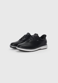 Une paire de baskets noires en cuir à lacets Skechers avec des semelles blanches, présentées sur un fond blanc uni.