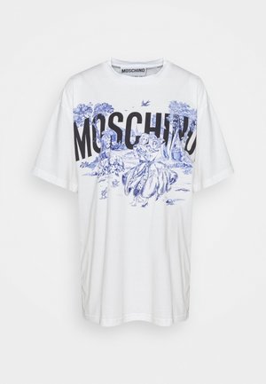 Vit bomullströja med blå tryckt design med träd och figurer, oversized passform, samt svart "MOSCHINO"-text över framsidan.