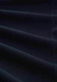 Ciemnoniebieska tkanina o gładkiej teksturze, prezentująca subtelne zagięcia i szwy. Materiał wydaje się wytrzymały i mocno tkany.