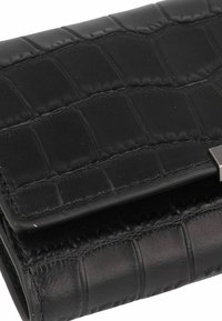 Portefeuille en cuir noir avec un motif crocodile, offrant un design pliant et des accents métalliques sur la fermeture. Détails de surface texturée.