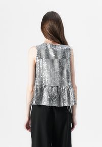 Čierno-biely károvaný peplum top s bezrukávovým dizajnom, textúrovanou tkaninou a zberaným pásom.