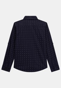 Marineblauw overhemd met lange mouwen, voorzien van een subtiel wit geometrisch patroon. Heeft een klassieke kraag en knoopmanchetten. Soepele stoftextuur.