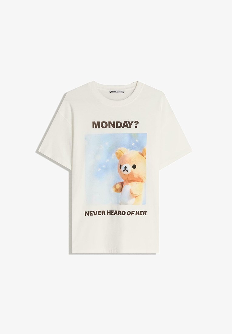 Hvid bomulds T-shirt med et grafisk motiv af en bjørn og teksten "MONDAY? NEVER HEARD OF HER" i brun, på en lyseblå baggrund.