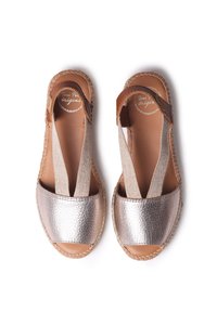 Kovové bronzové espadrilky s elastickými popruhmi, prírodné hnedé kožené akcenty a jútové podrážky. Hladký povrch a dizajn s otvorenou špičkou.