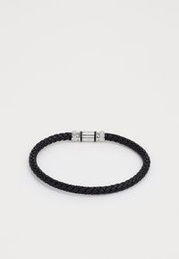 Bracelet en cuir tressé noir avec un fermoir en métal argenté présentant des accents nervurés et un détail central. Forme circulaire simple avec une texture lisse.