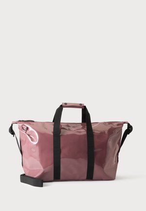 Γυαλιστερή μεγάλη τσάντα duffel σε μωβ χρώμα με μαύρες λαβές και ρυθμιζόμενο ιμάντα ώμου σε απλό ανοιχτό φόντο.