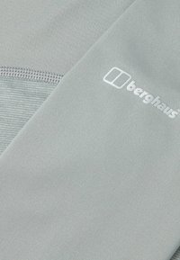 Lichtgrijze prestatiekatoen met een gestructureerd ontwerp, een gladde afwerking en een wit Berghaus-logo dat prominent is gepositioneerd.