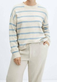 Maglione beige a righe con strisce orizzontali blu chiaro, colletto rotondo, polsini e orlo a coste, abbinato a pantaloni beige chiaro.