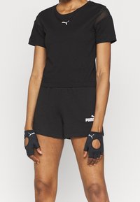 Czarny strój sportowy składający się z krótkiego topu, dopasowanych szortów oraz rękawic bez palców z siateczkowymi akcentami i białymi detalami logo.