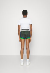 White short-sleeved shirt with a ribbed texture, paired with green and black mesh athletic shorts featuring blue accents and an elastic waistband.