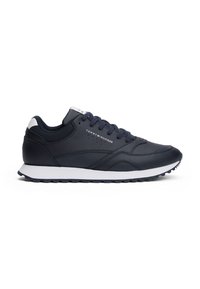 Baskets de sport bleu marine avec une tige en cuir lisse, semelle blanche, accents texturés et une marque bien visible sur le côté. Design à lacets.