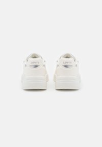 Vita sneakers med en slät läder- och meshinning, silverdetaljer på hälen och sidan, samt en texturerad gummisula.