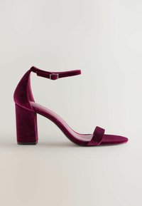 Bordeaux fluwelen sandaal met hoge hak, vierkante blokhak, enkelbandje en een slanke voetbed. Glad textuur met een minimalistisch ontwerp.